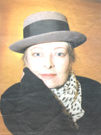 Kim Haueter in a grey felt hat, black coat and leopard-print scarf